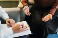 Two people in a therapy meeting, one taking notes.